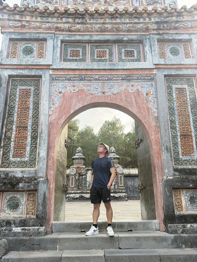 Standing under a gate at the imperial tombs in Huế, Vietnam